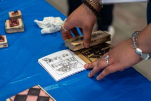 Hands stamping block prints into a notebook