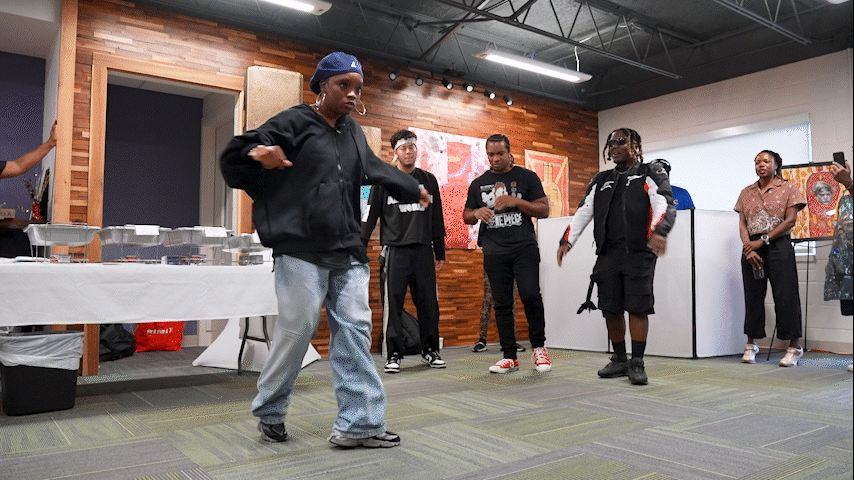 A dancer spins around with her crew supporting her in the background