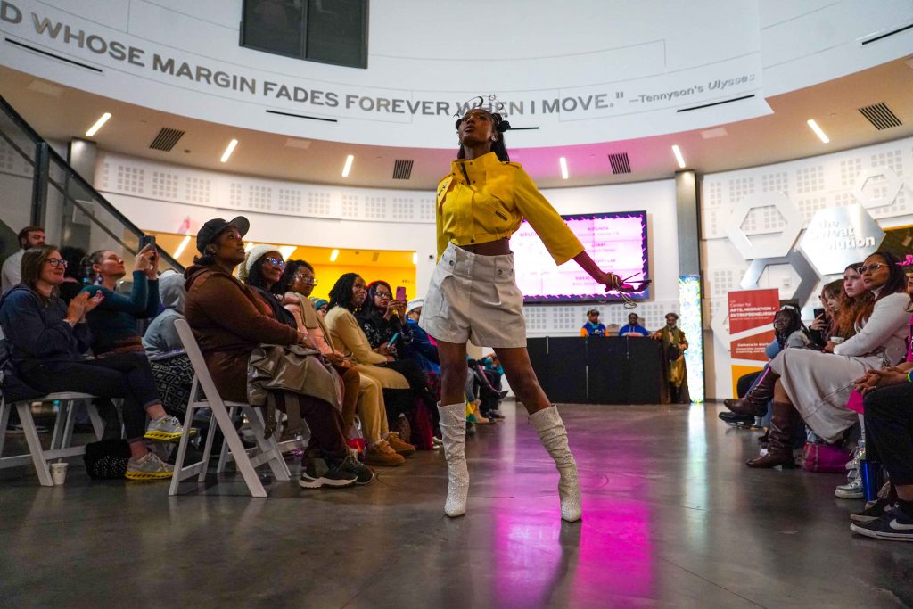 A model on a runway in front of a crowd in the cade museum.